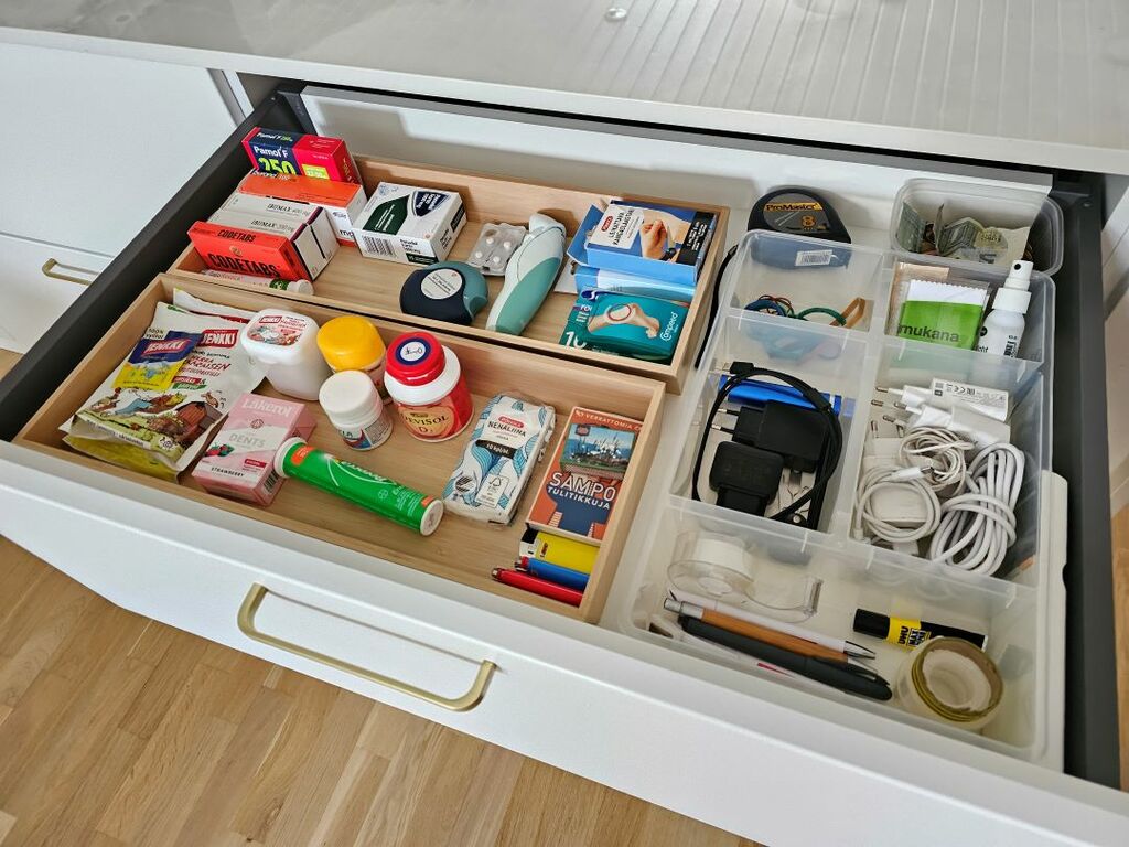 Sekatavaralaatikon tavarat on karsittu ja järjestetty toimivaan järjestykseen. Päivittäin käytettävät vitamiinit, lääkkeet ja laturit ovat helposti saatavilla.