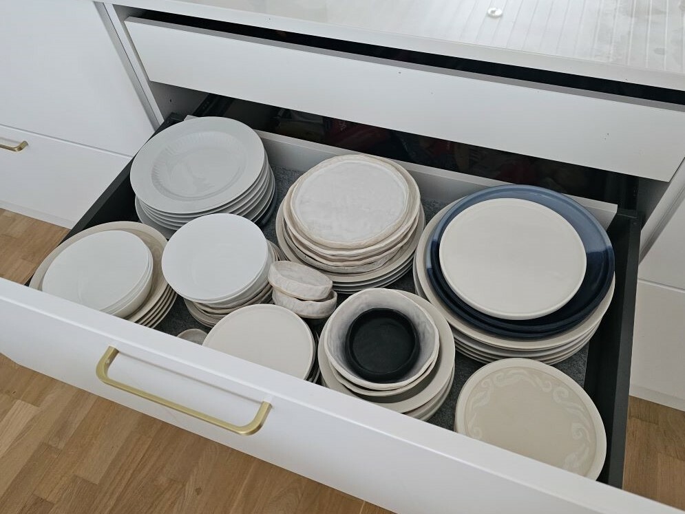 Keittiön vetolaatikko on täynnä erilaisia ja eriparisia lautasia.